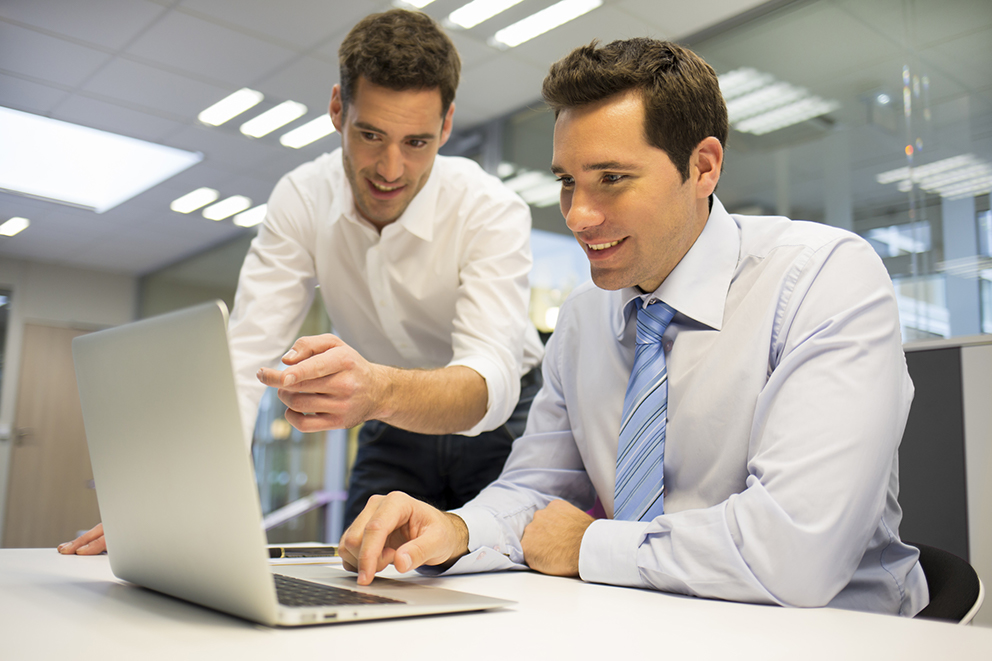 Man teaching another man on a computer